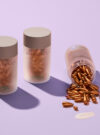 Exuviance produkten vitamin C serum capsules står på rad, den sista ligger ner och det trillar ut kapslar.