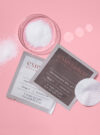 Exuviance produkten performance peel AP25 visas upp med ingredienser runt omkring mot en rosa bakrund.