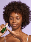 Exuviance kvinna ler och pumpar ut produkten radiance serum I sin hand.