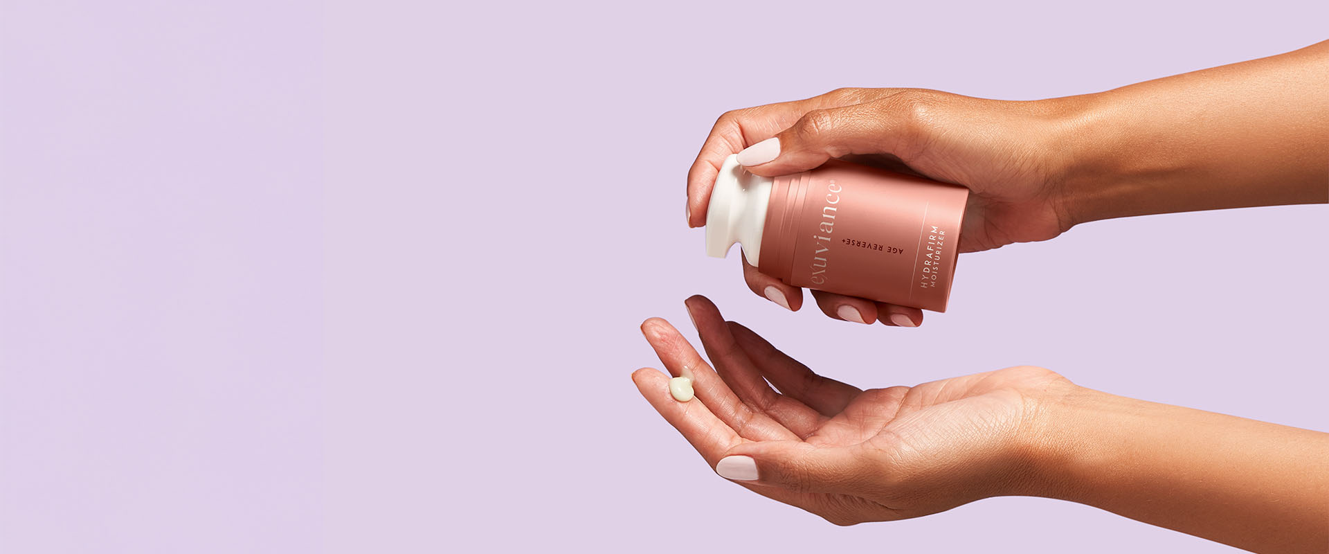 Två händer som trycker ut kräm från produkten Age Reverse HydraFirm Moisturizer.