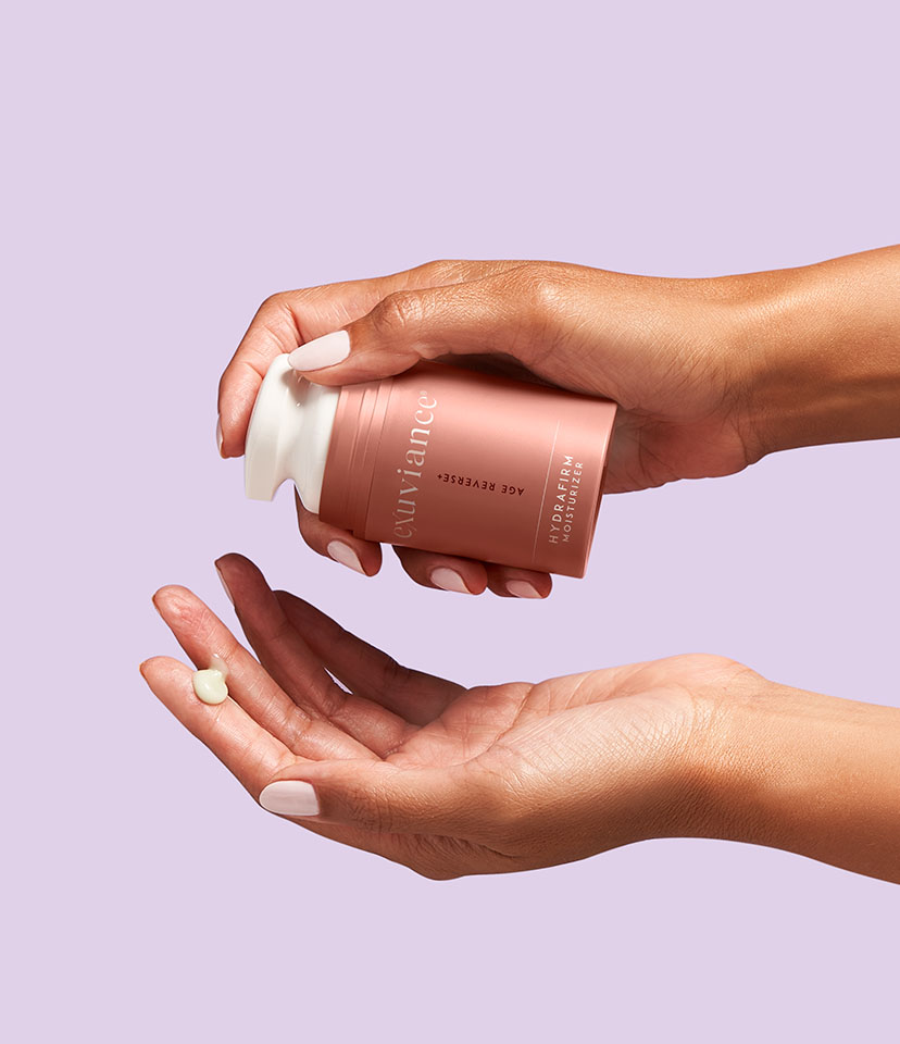 Två händer som trycker ut kräm från produkten Age Reverse HydraFirm Moisturizer.