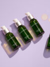 Exuviance produkten radiance serum ligger på en rad mot en lila bakrund.