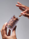 En hand plockar ut en kaplsen från produkten vitamin C serum capsules.