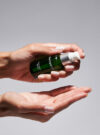 Två händer håller i radiance serum och pumpar ut produkten.
