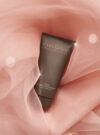 Exuviance produkten triple microdermabrasion face polish ligger i ett rosa tyg.