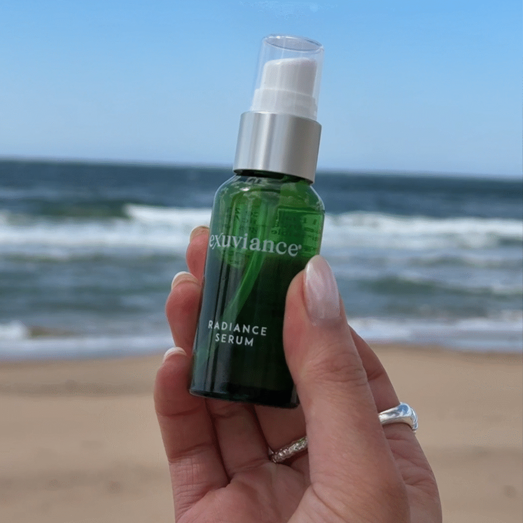 Hand som håller upp Radiance Serum framför havet.